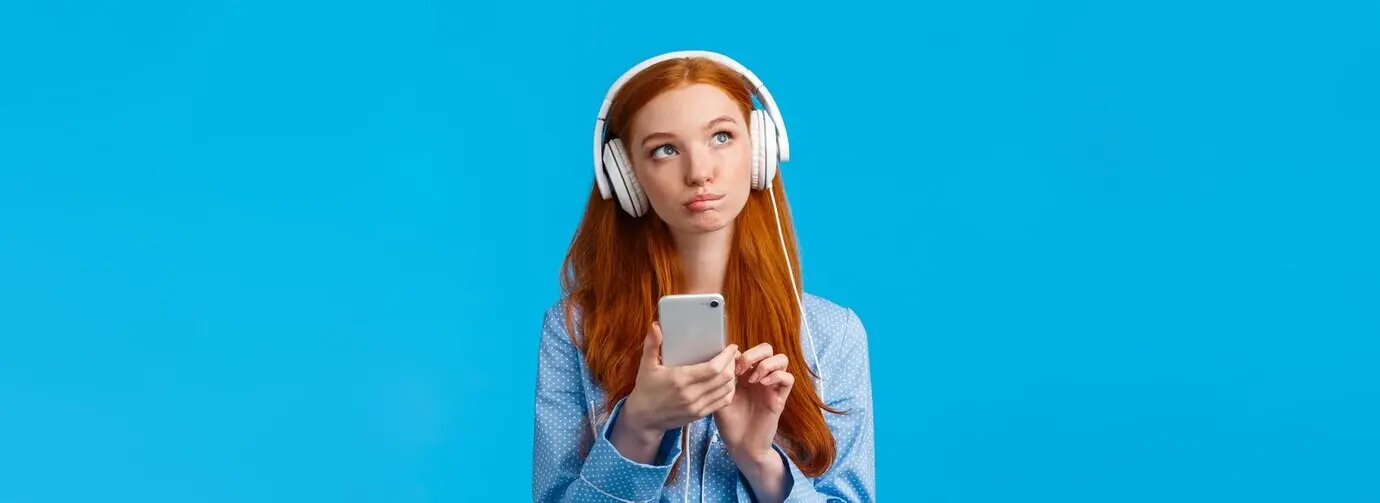 Задумчивая и творческая рыжеволосая женщина европейской внешности, рыжая девушка в ночной одежде, смотрит вверх, размышляя.